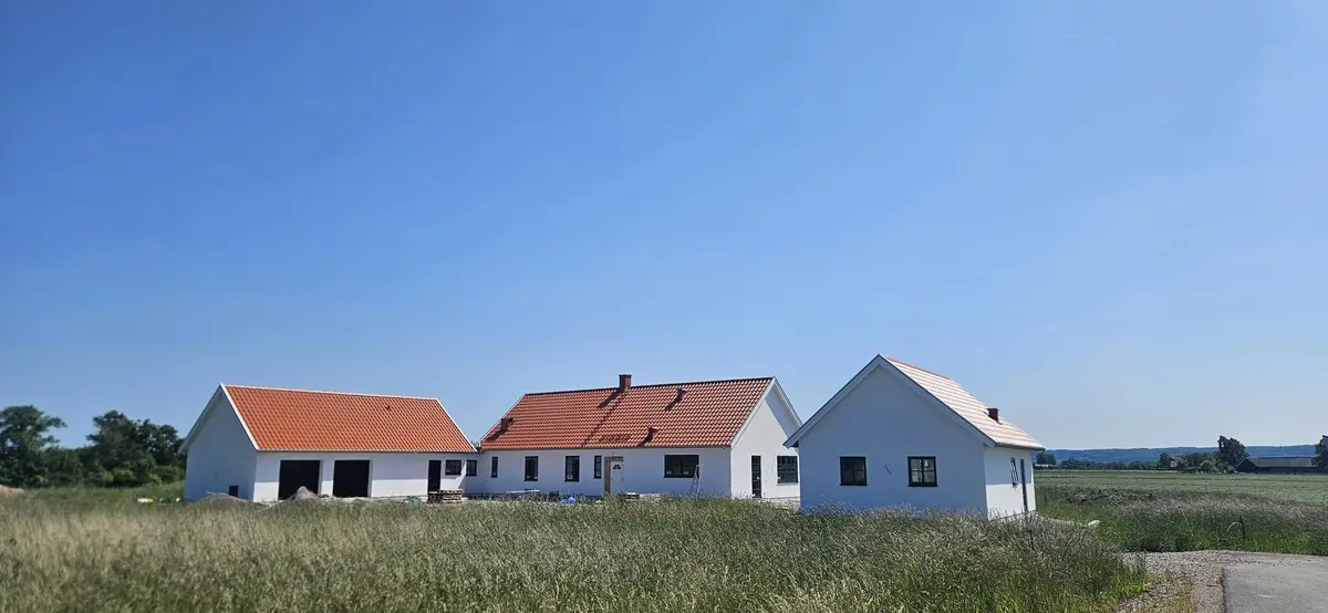 Nyproducerad vit villa med tegeltak i öppet landskap